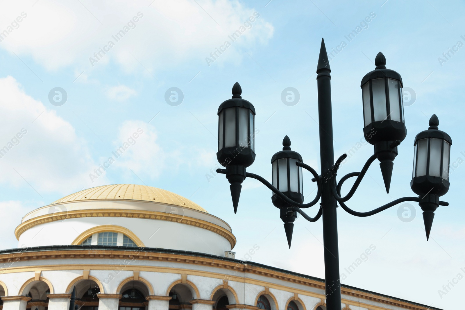 Photo of Old fashioned street light lamp near building against cloudy sky