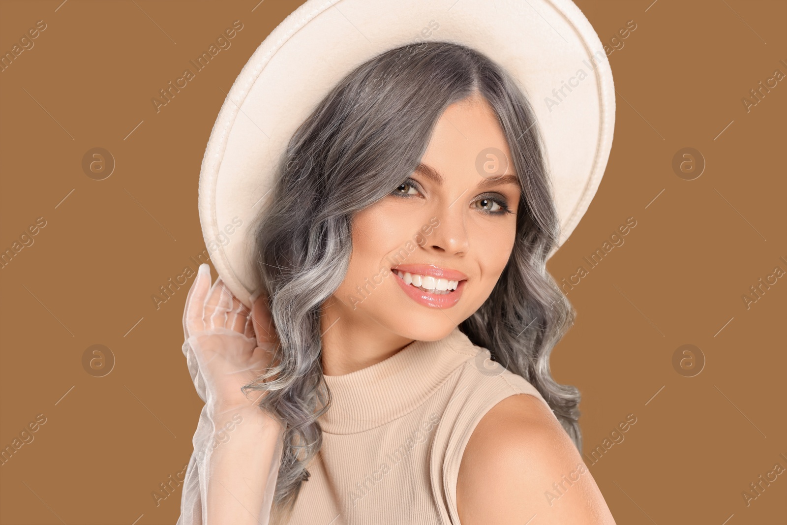 Image of Portrait of smiling woman with ash hair color on light brown background