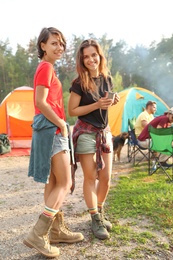Young women near camping tents in wilderness