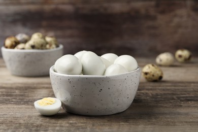Photo of Many peeled hard boiled quail eggs in bowl on wooden table, closeup