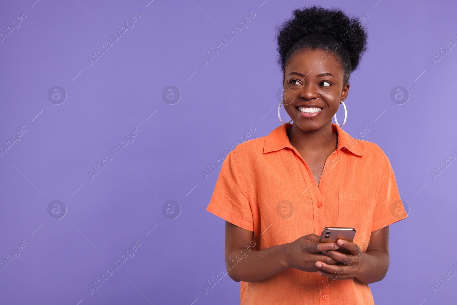 Photo of Happy young woman with smartphone on purple background. Space for text