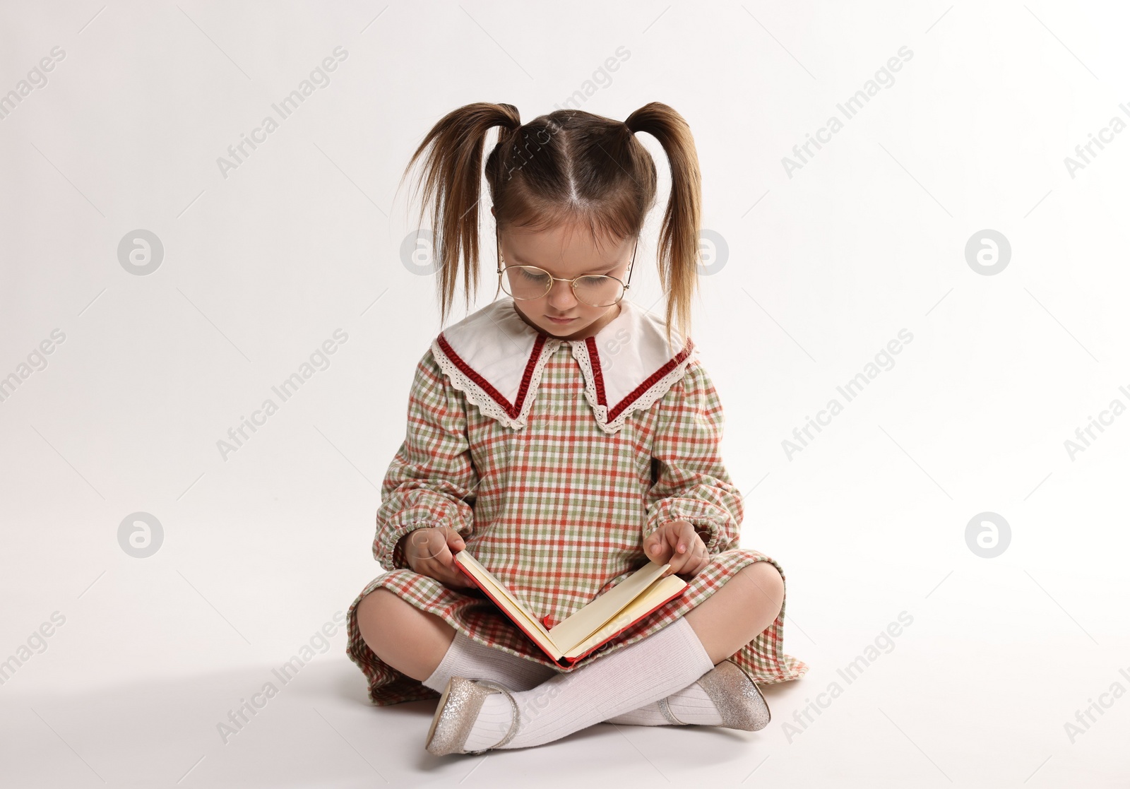 Photo of Cute little girl reading book on white background