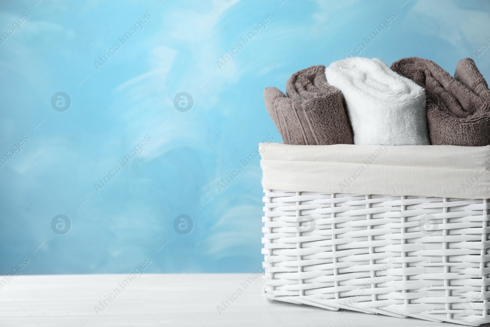 Photo of Basket with soft bath towels on table. Space for text