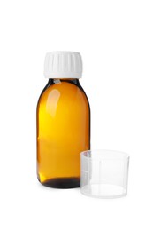 Bottle of syrup with measuring cup on white background. Cough and cold medicine