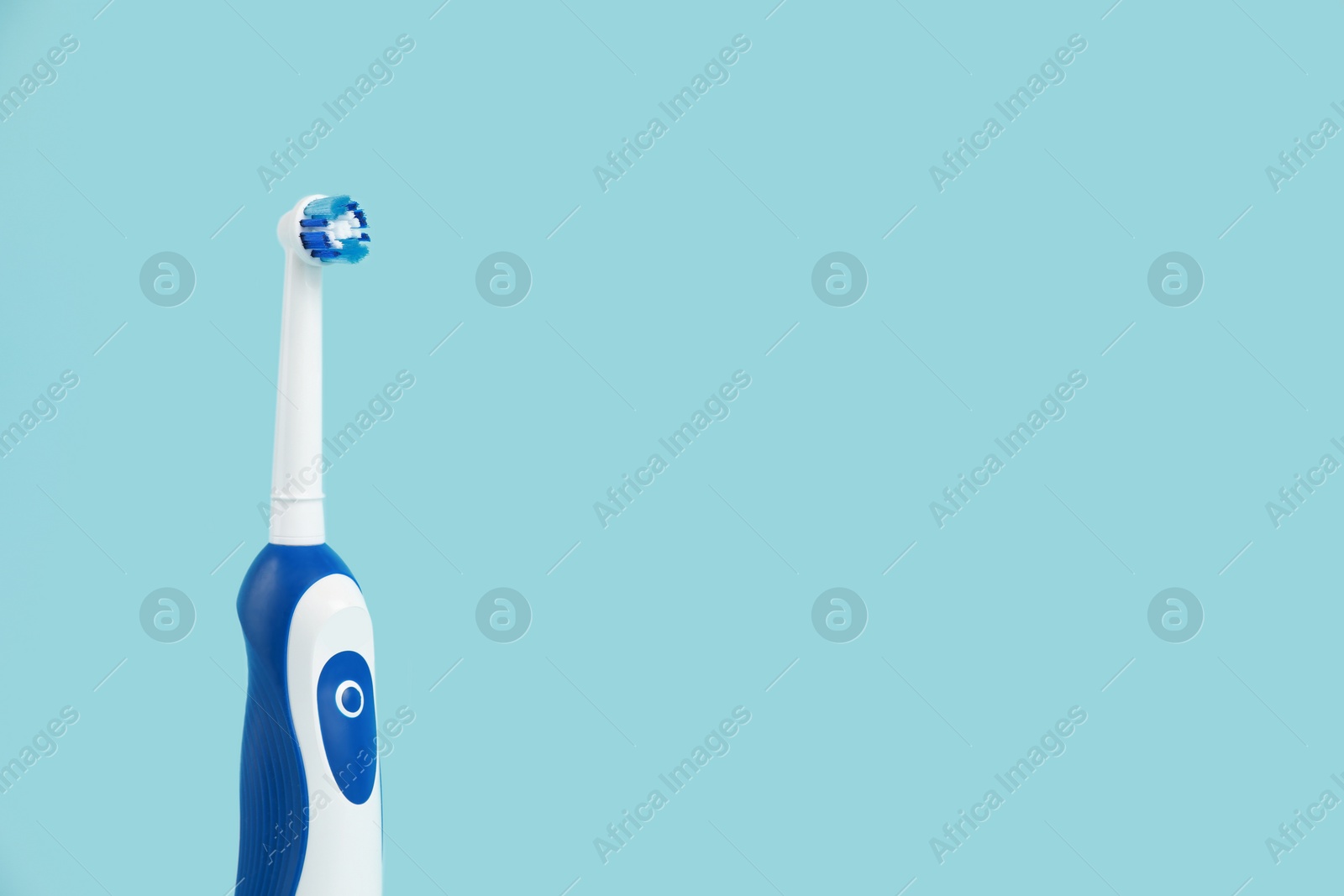 Photo of Electric toothbrush on light blue background, space for text