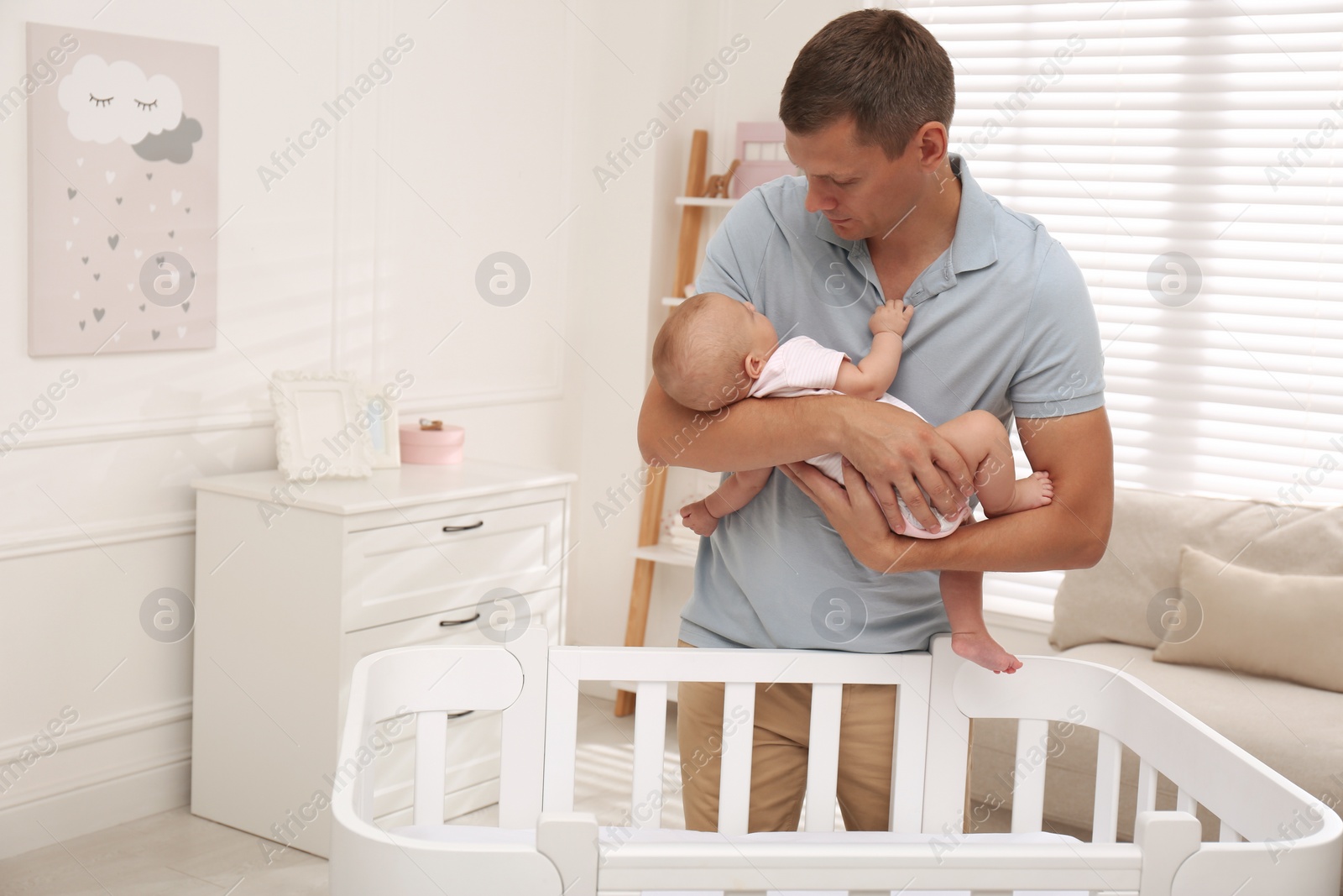 Photo of Happy father with his cute sleeping baby near crib at home