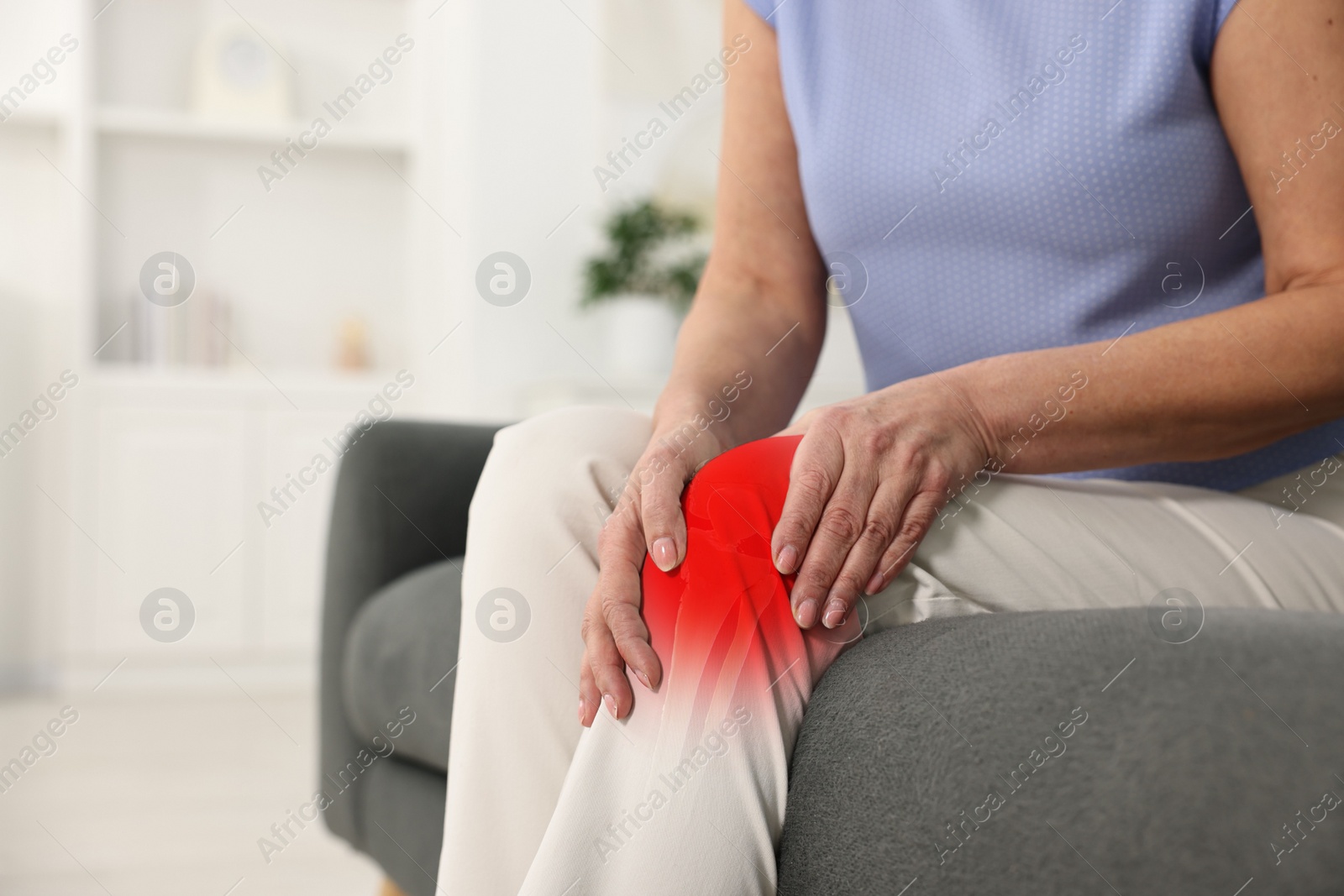 Image of Arthritis symptoms. Woman suffering from pain in her knee on sofa indoors, closeup. Space for text