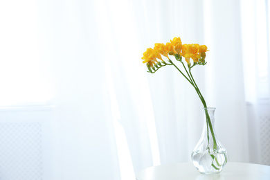 Photo of Beautiful yellow freesia flowers on table indoors. Space for text