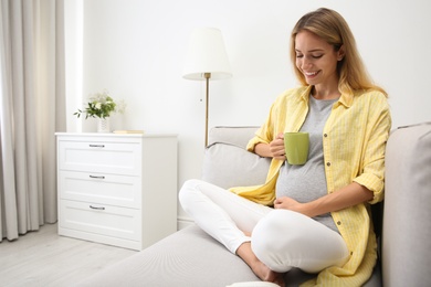 Beautiful pregnant woman drinking tea at home