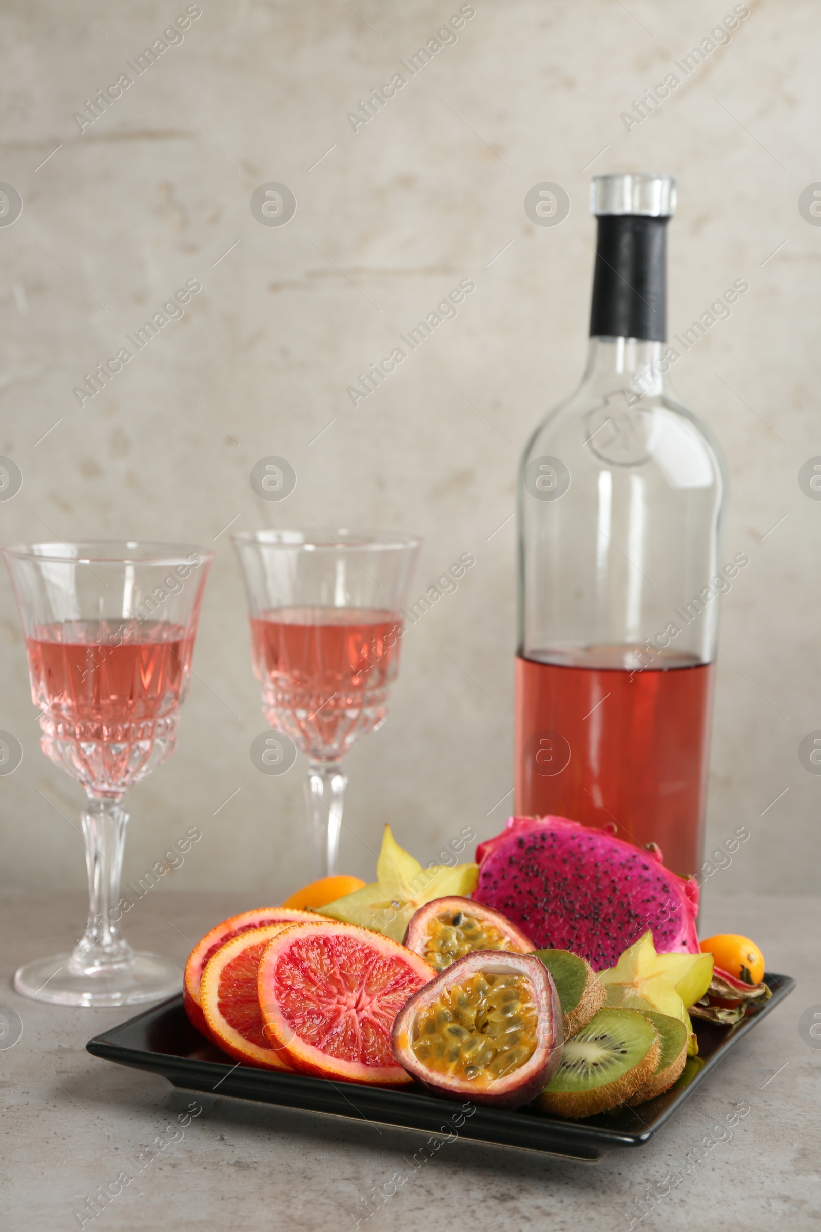 Photo of Delicious exotic fruits and wine on grey table