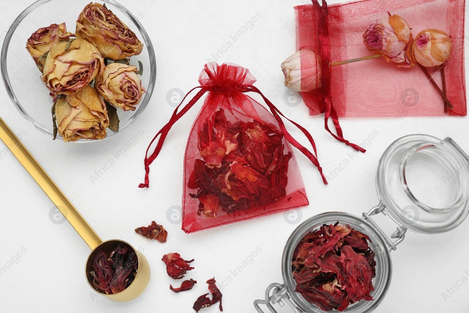 Photo of Scented sachets with dried rose and hibiscus flowers on white table, flat lay