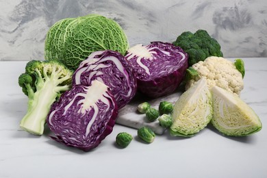 Photo of Many different types of cabbage on white marble table