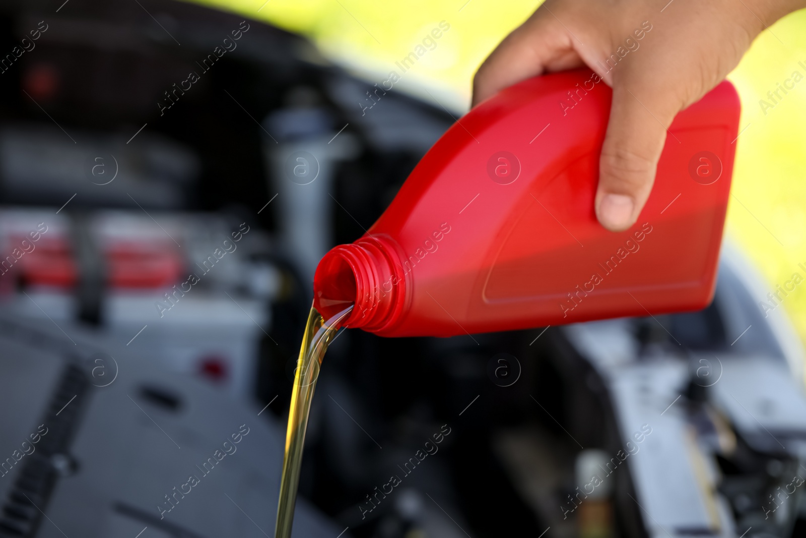 Photo of Man pouring motor oil from red container, closeup