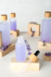 Photo of Bottles of lavender essential oil and flowers on wooden table