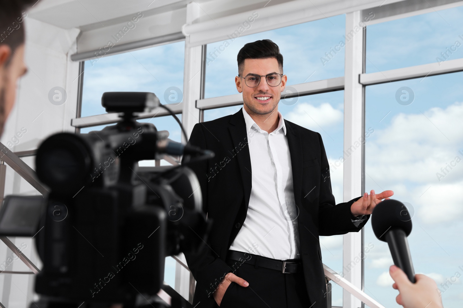 Photo of Happy business man talking to journalists indoors