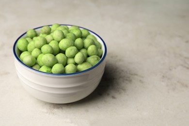Tasty wasabi coated peanuts in bowl on table, space for text