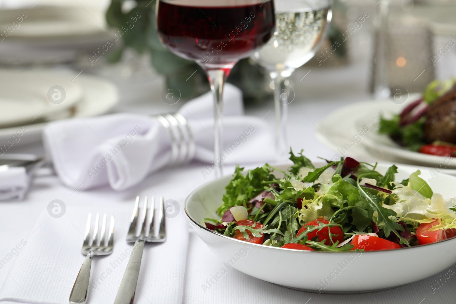 Photo of Delicious salad and wine served on table in restaurant