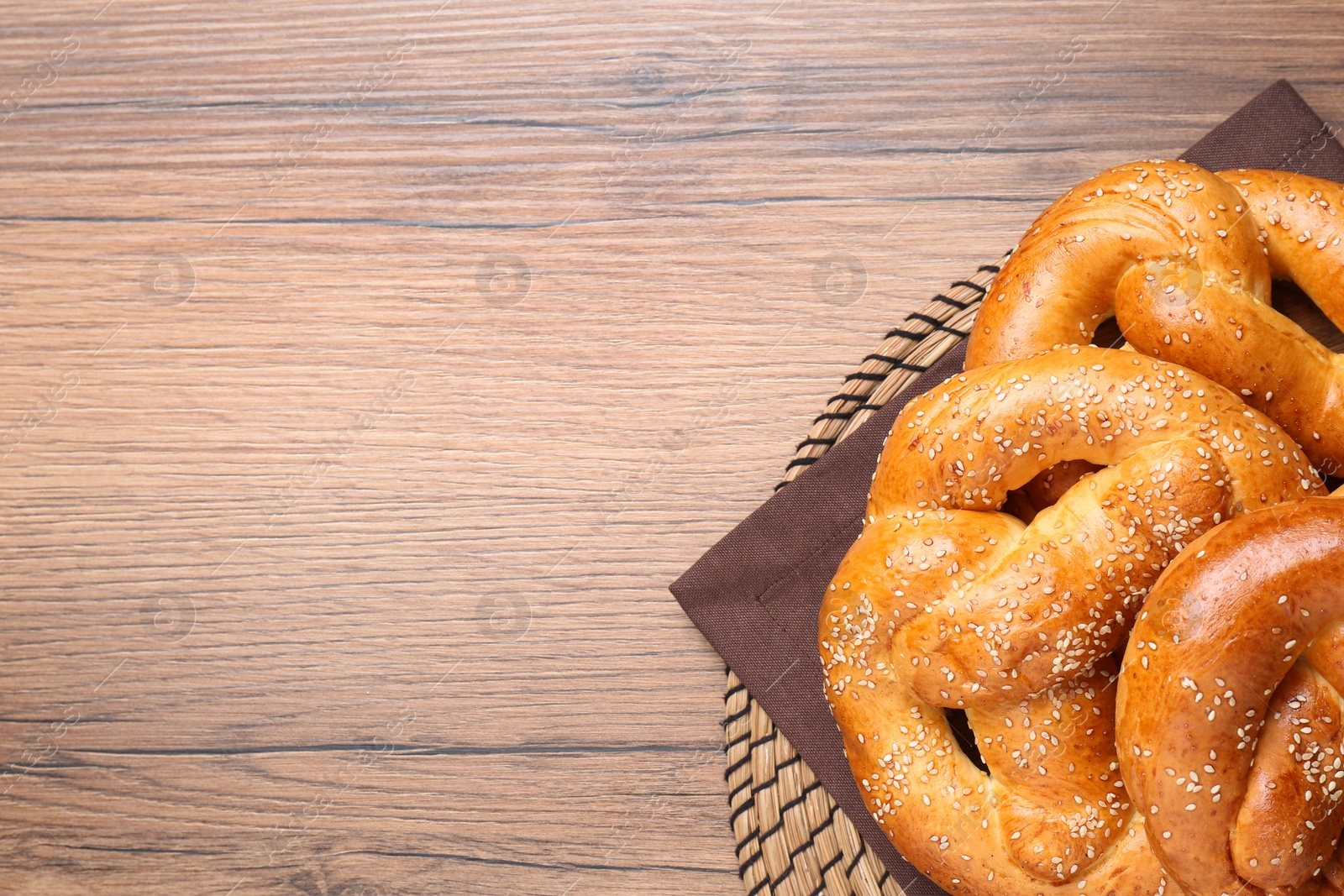 Photo of Delicious pretzels with sesame seeds on wooden table, top view. Space for text