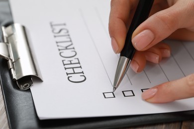 Photo of Woman filling Checklist at table, closeup view