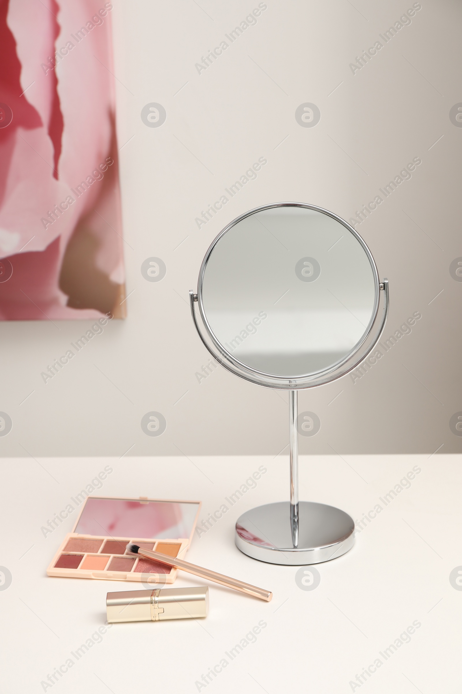 Photo of Mirror and cosmetic products on white dressing table