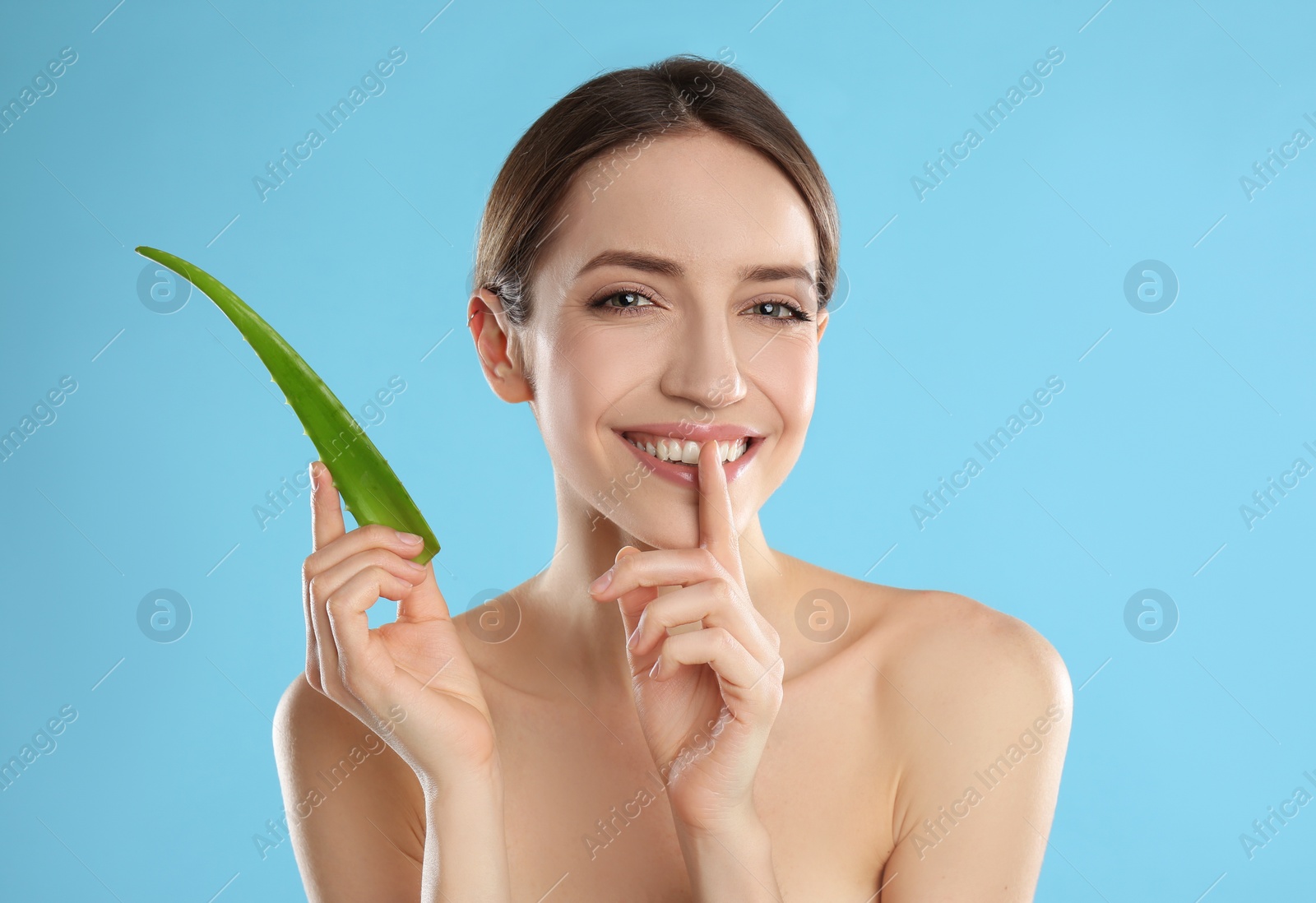 Photo of Happy young woman with aloe leaf on light blue background