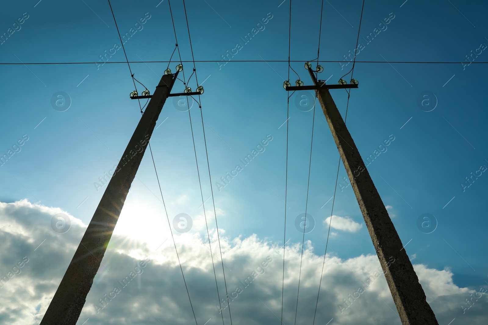 Photo of Telephone poles and wires against blue sky with clouds