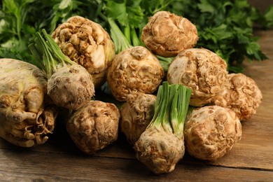 Photo of Fresh raw celery roots on wooden table, closeup