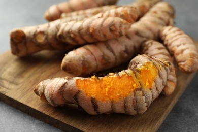 Many raw turmeric roots on grey table, closeup