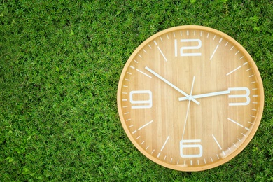 Big clock on green plants, outdoors. Time change concept