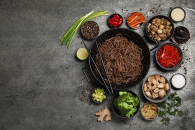 Photo of Wok with noodles, chicken and other products on grey table, flat lay. Space for text