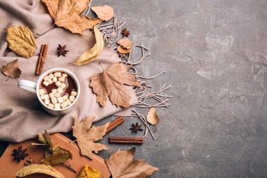 Flat lay composition with cup of hot drink and autumn leaves on grey table, space for text. Cozy atmosphere