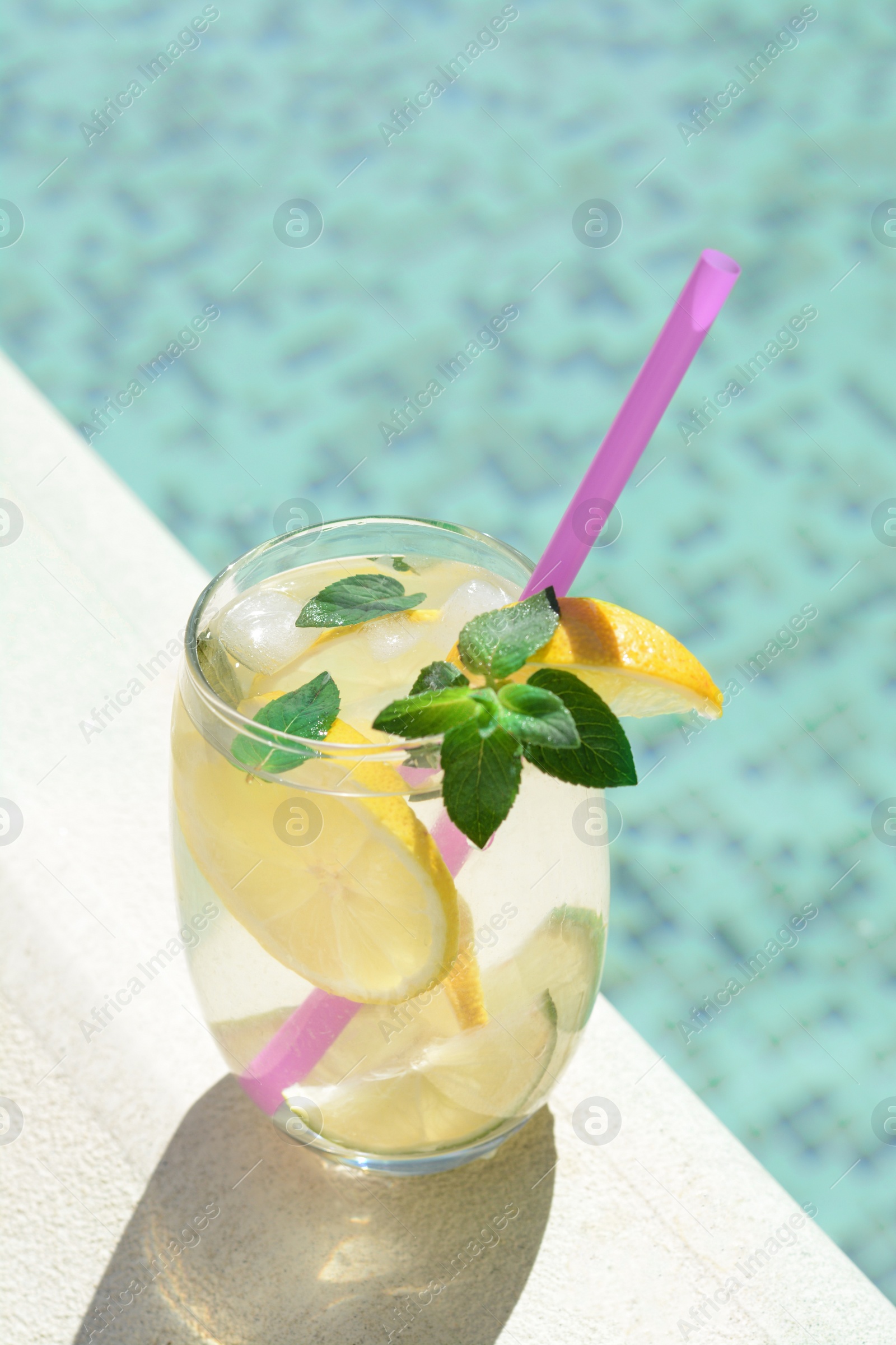 Photo of Refreshing drink with citrus slices and mint near swimming pool