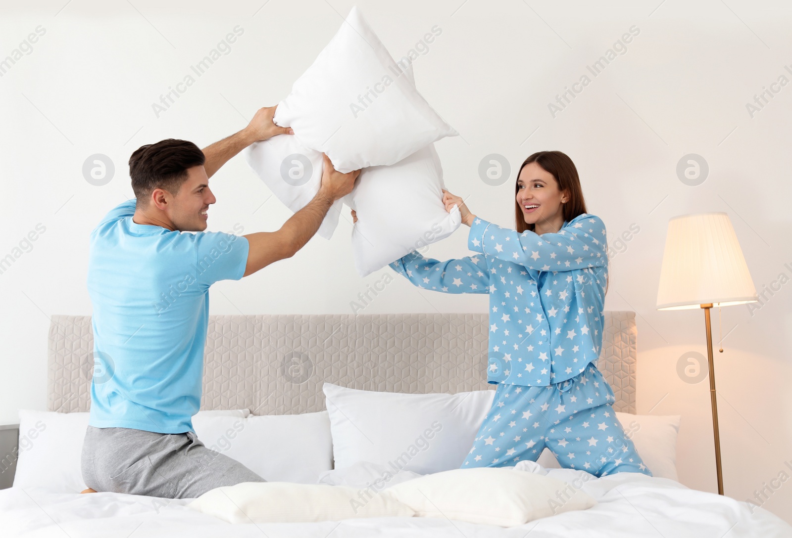 Photo of Happy couple having pillow fight in bedroom