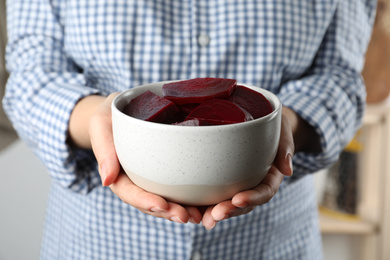 Woman holding bowl of pickled beets, closeup