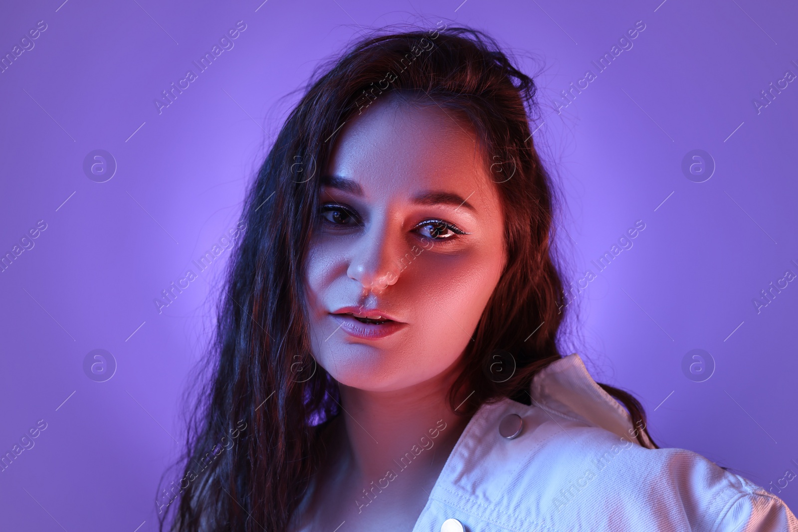 Photo of Portrait of beautiful young woman on color background with neon lights