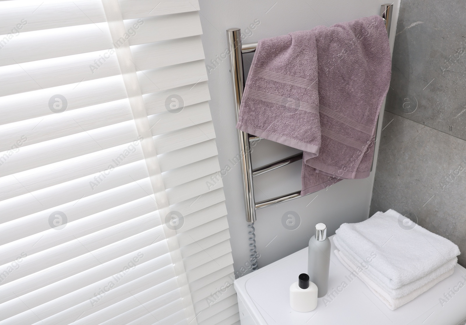 Photo of Clean terry towel on heated rail in bathroom