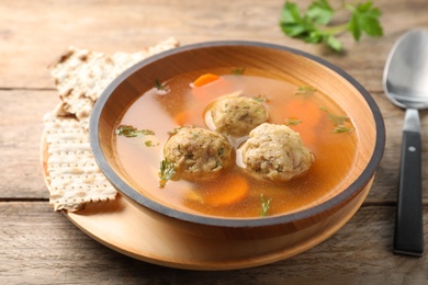 Photo of Bowl of Jewish matzoh balls soup on wooden table