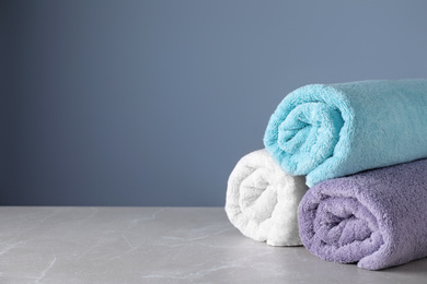 Photo of Fresh rolled bath towels on grey table. Space for text