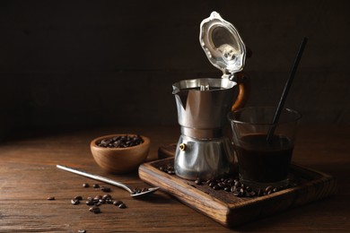 Brewed coffee, moka pot and beans on wooden table, space for text