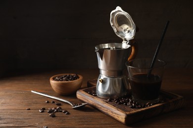 Photo of Brewed coffee, moka pot and beans on wooden table, space for text