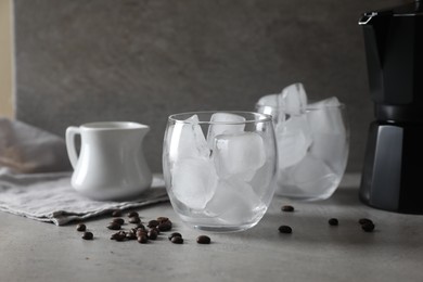 Photo of Making iced coffee. Ice cubes in glasses and ingredients on gray table, closeup