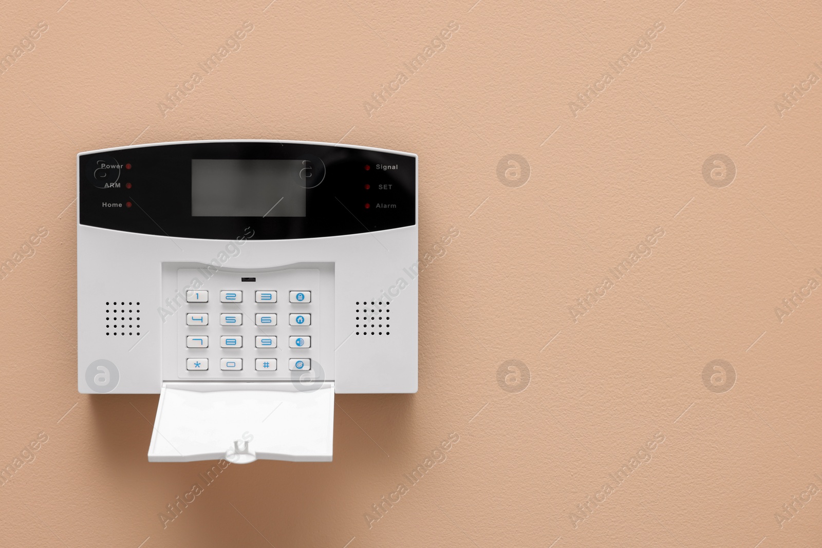 Photo of Home security alarm system on beige wall, space for text