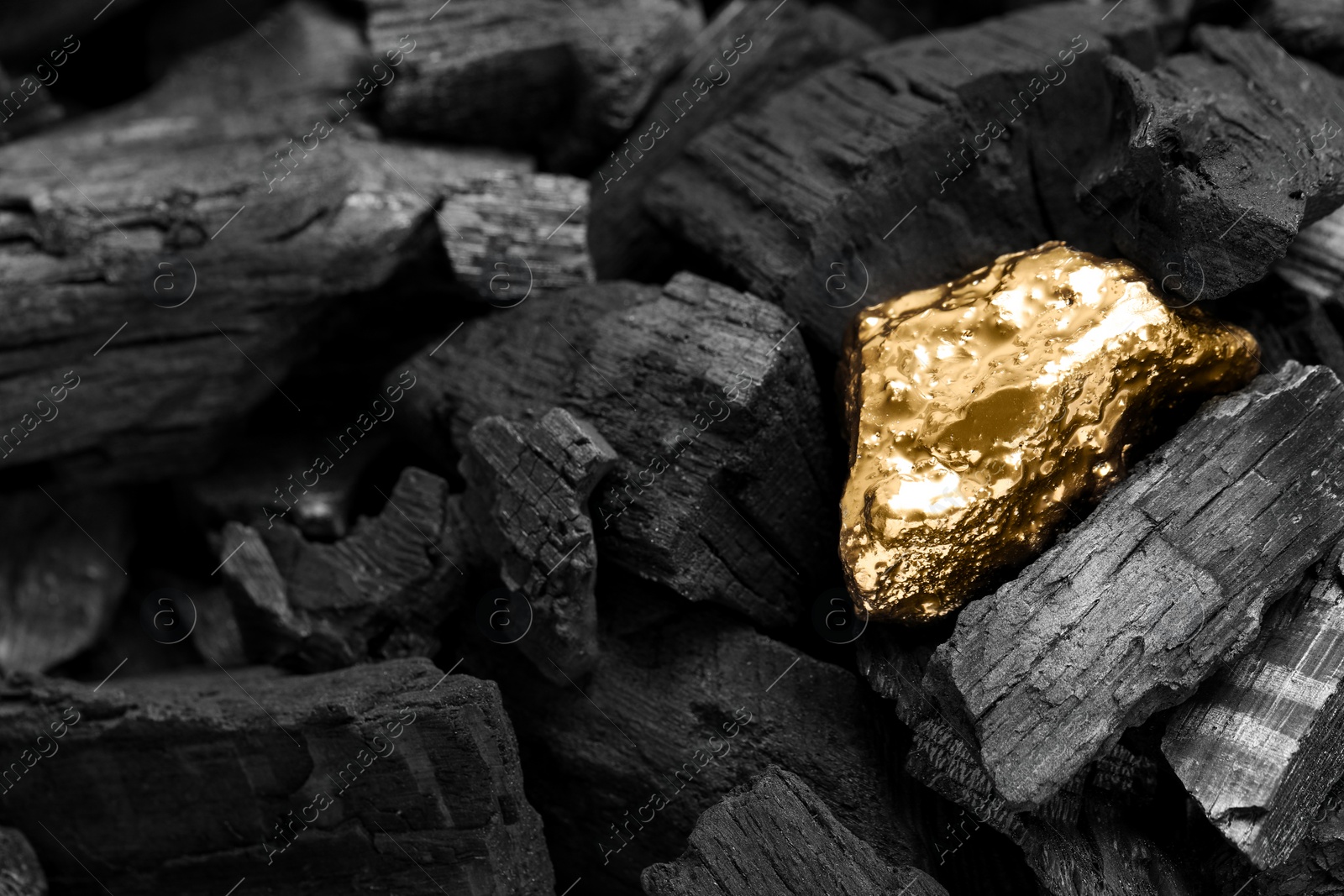 Photo of Shiny gold nugget on coals, closeup view