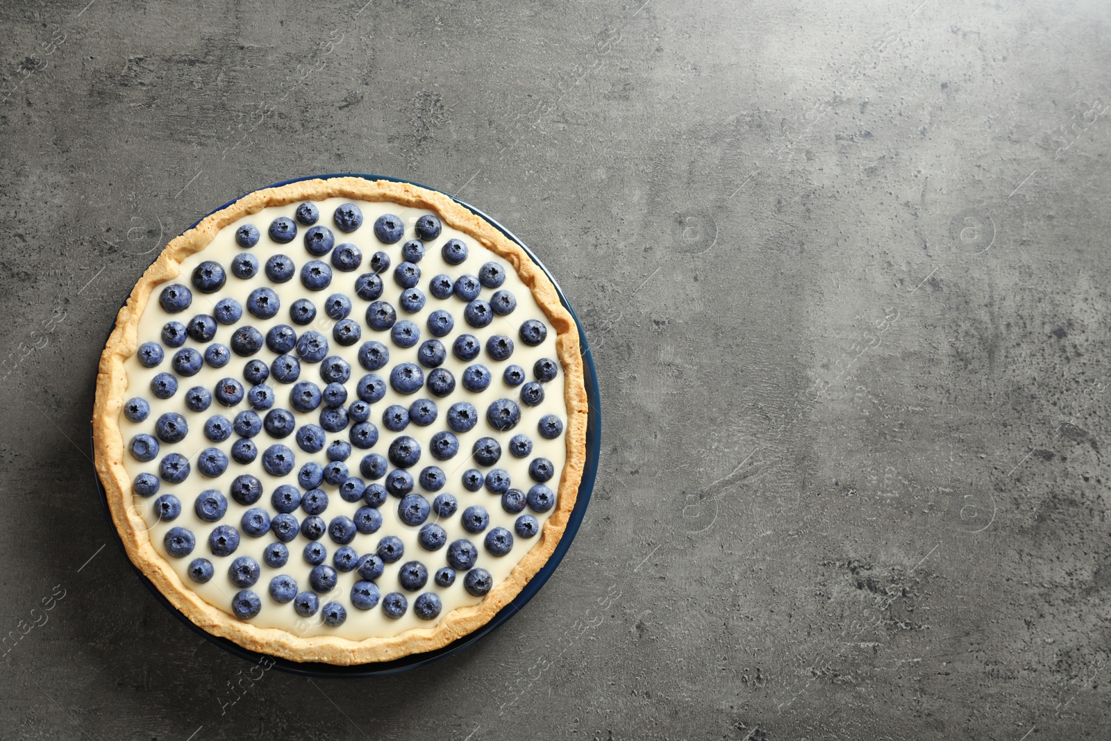 Photo of Tasty blueberry cake on gray background, top view with space for text