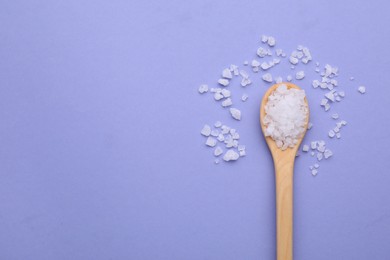 Photo of Spoon with sea salt on violet background, top view. Space for text