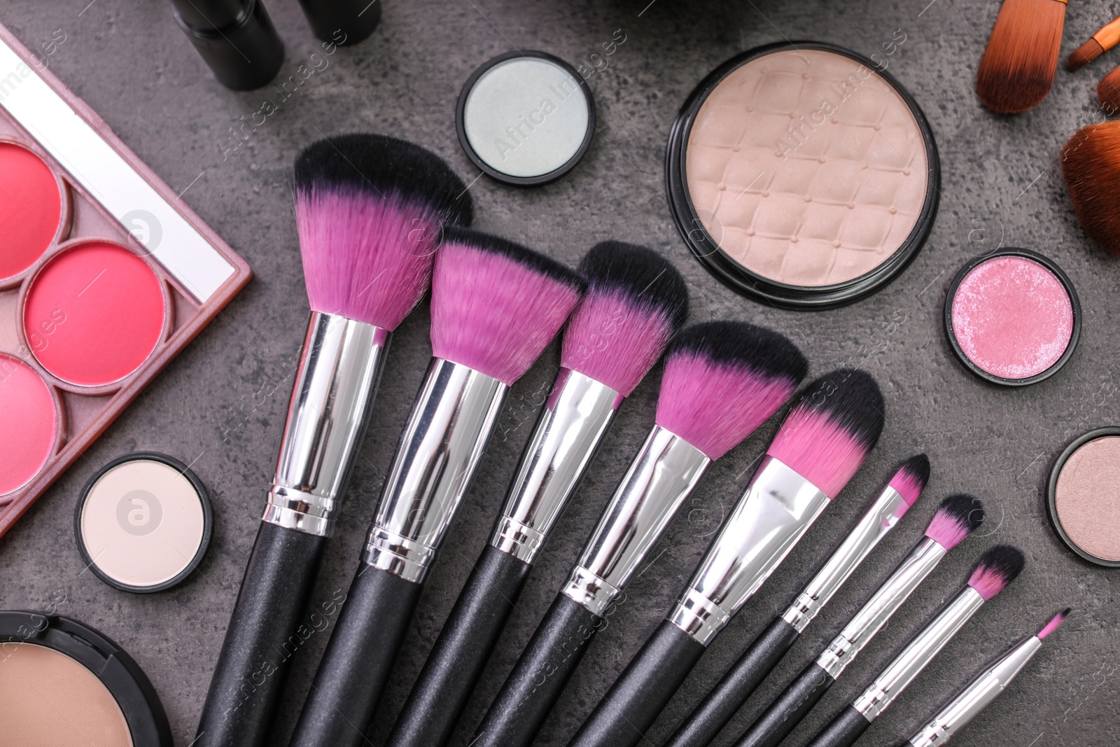 Photo of Makeup products and brushes on grey background