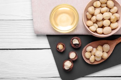 Delicious organic Macadamia nuts and natural oil on white wooden table, top view. Space for text