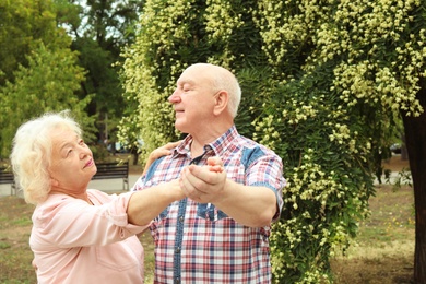 Cute elderly couple in love dancing outdoors