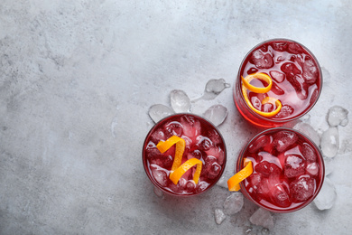 Photo of Fresh Negroni cocktails with orange zest on grey table, flat lay. Space for text