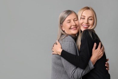 Photo of Family portrait of young woman and her mother on grey background. Space for text